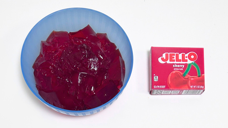 A bowl of gelatin next to a packet of Jell-O Cherry