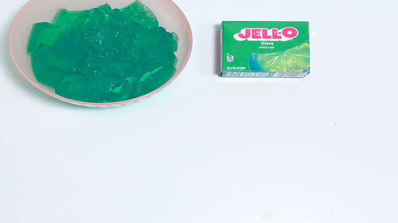A bowl of gelatin next to a packet of Jell-O Lime