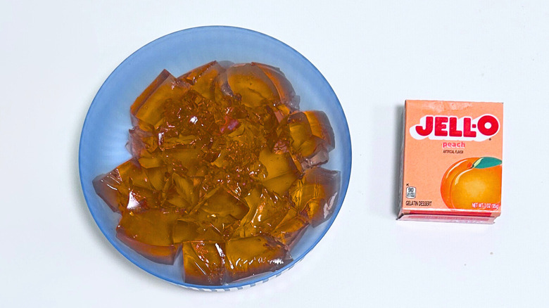 A bowl of gelatin next to a packet of Jell-O Peach