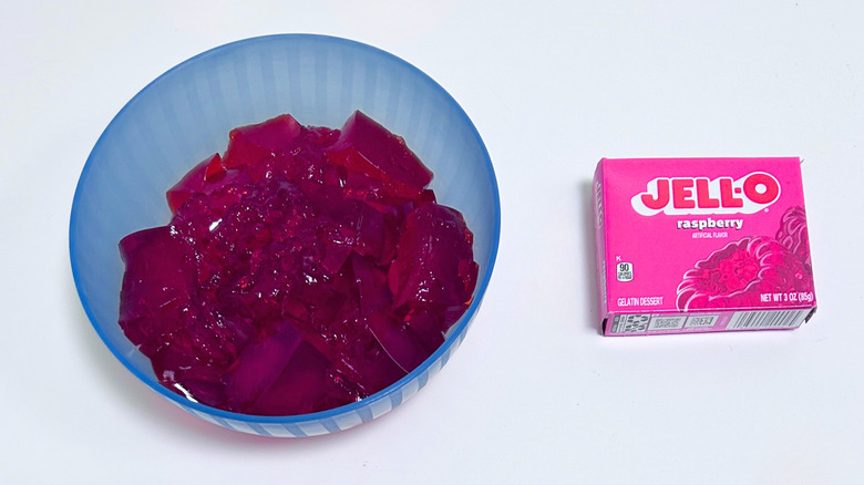 A bowl of gelatin next to a packet of Jell-O Raspberry