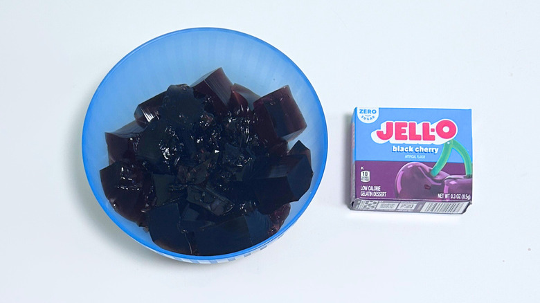 A bowl of gelatin next to a packet of Jell-O Zero Sugar Black Cherry