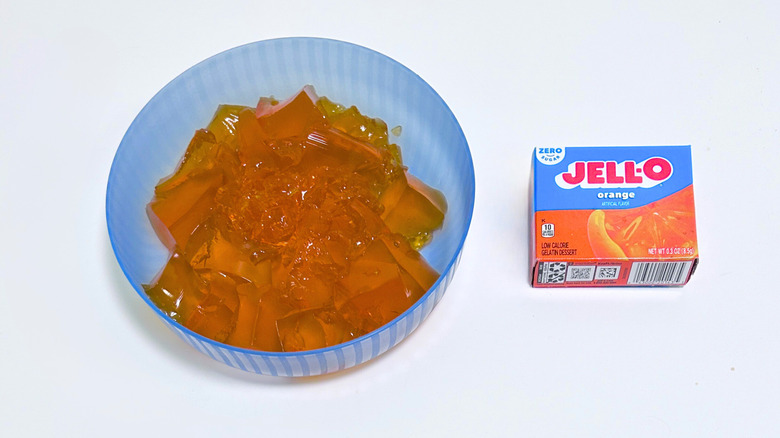 A bowl of gelatin next to a packet of Jell-O Zero Sugar Orange
