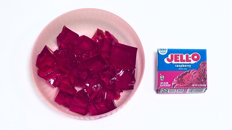 A bowl of gelatin next to a packet of Jell-O Zero Sugar Raspberry