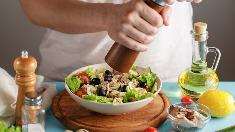 Chef adding pepper to tuna salad