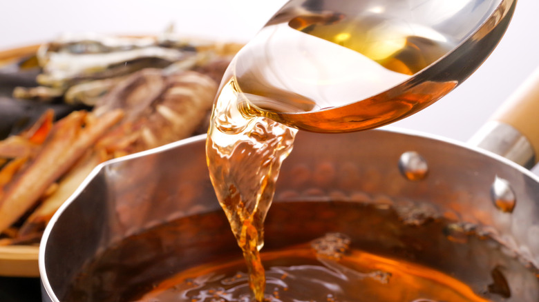 Broth being poured into a stock pot with a blurred background