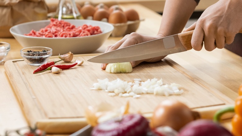 Hands chopping onion with knife