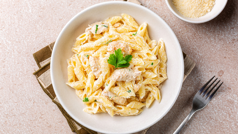Chicken penne Alfredo in white bowl with fork
