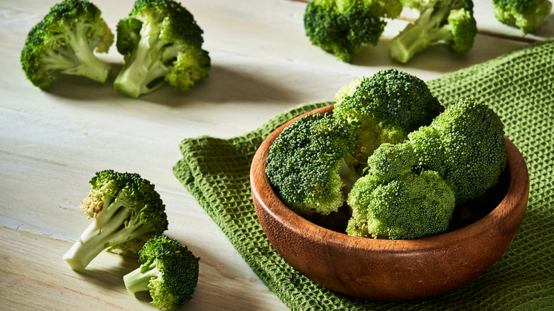 Fresh raw broccoli in bowl on rustic table