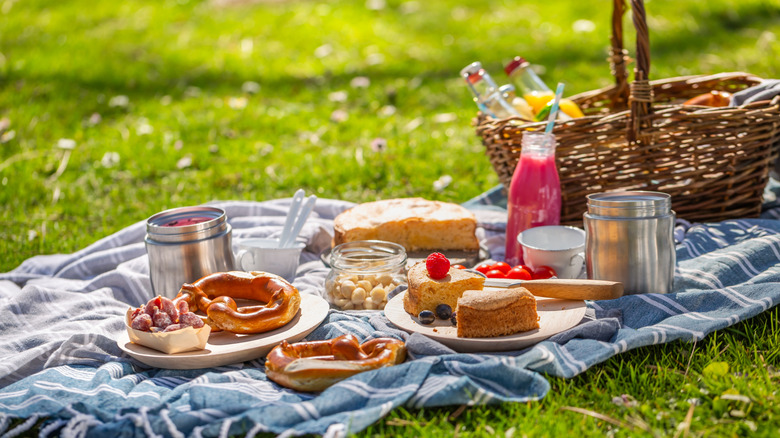 Blue blanket with picnic basket and picnic foods spread out on it
