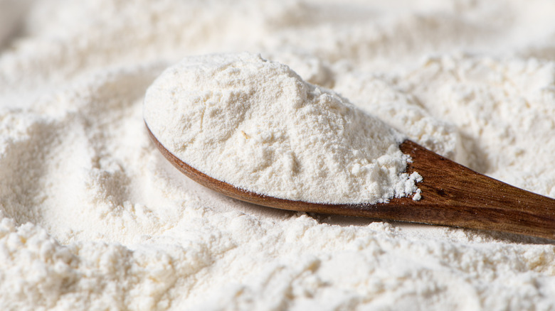 a wooden spoon with a scoop of white flour.