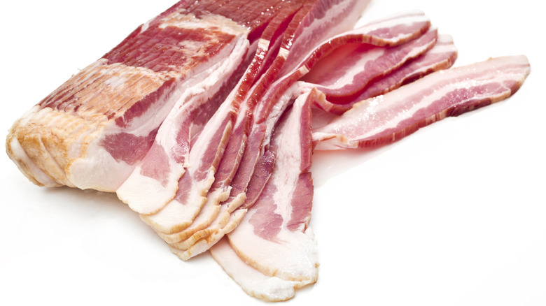 thick slices of raw bacon on a white background.