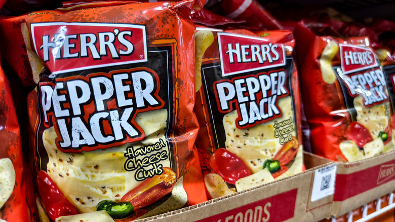 A row of Herr's Pepper Jack Cheese Curls on a store shelf.