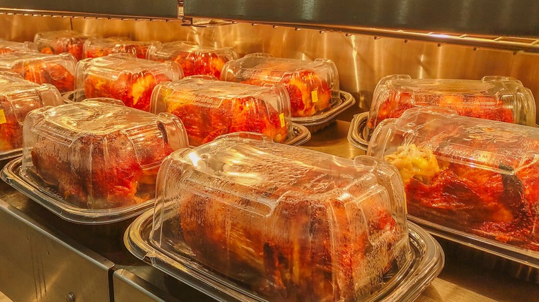 Rotisserie chickens packed in containers and stored under heat lamps