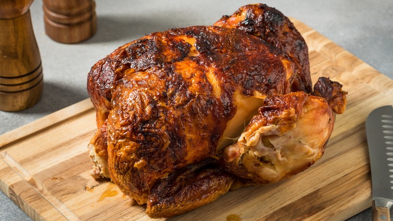 Rotisserie chicken on a wooden board with a knife
