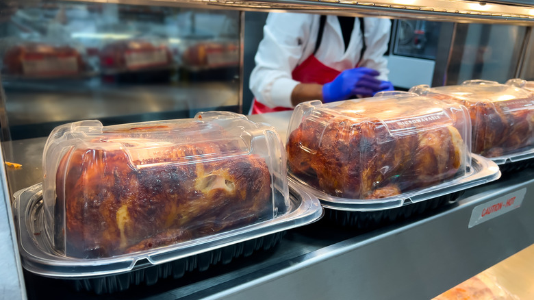 A few rotisserie chickens packed in take out containers on display