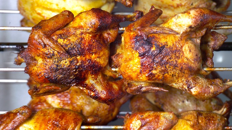 Rotisserie chickens fixed on rods cooking in a rotisserie oven