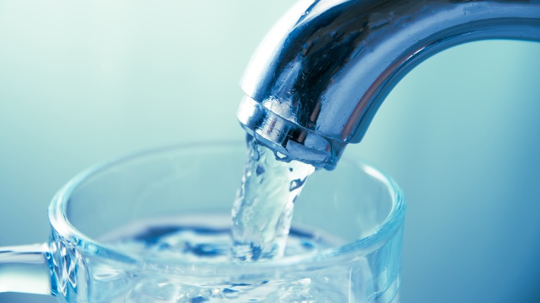 Closeup of tap water flowing into a glass