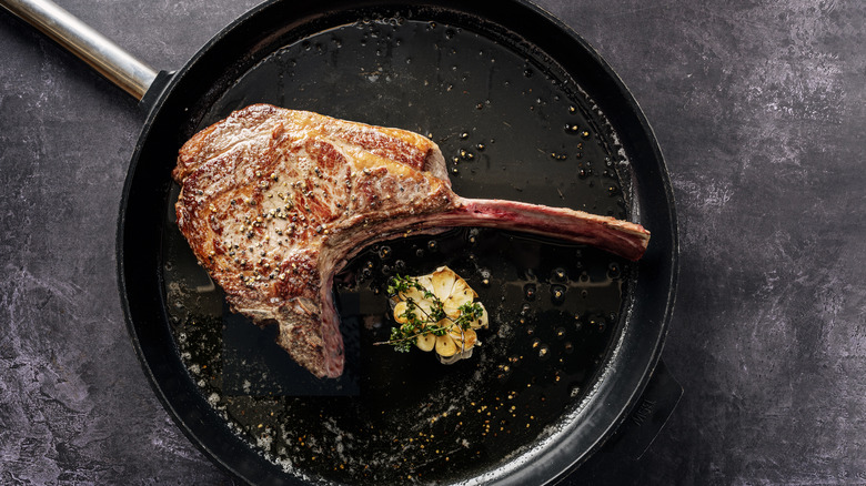 Tomahawk steak frying in pan