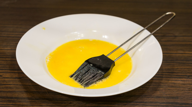 Egg wash in white bowl, with brush