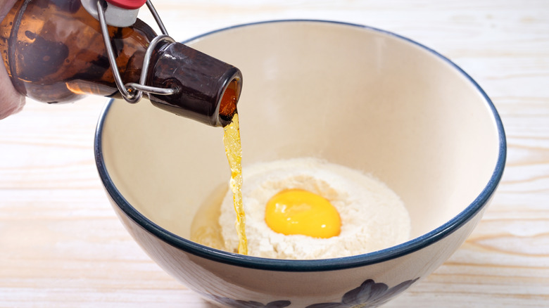 Beer batter ingredients in bowl, with beer being poured in