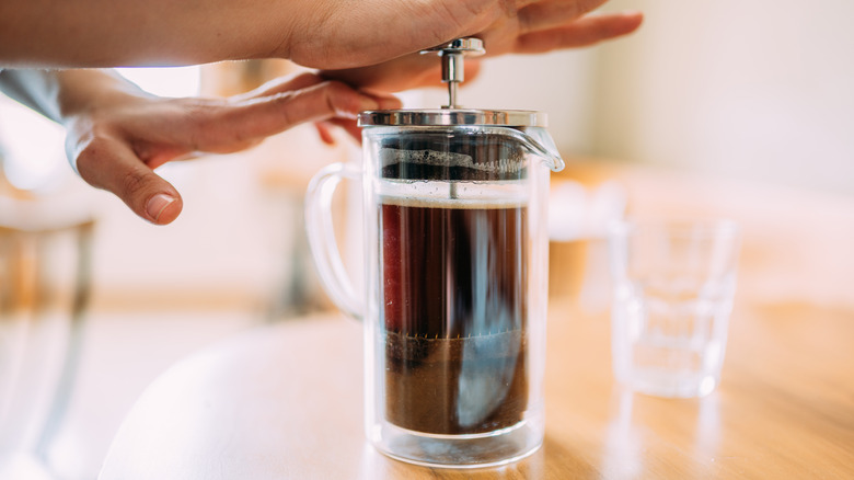 person making french press coffee