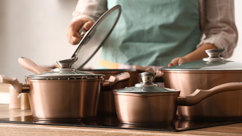 A woman checking copper pots placed on a wooden table