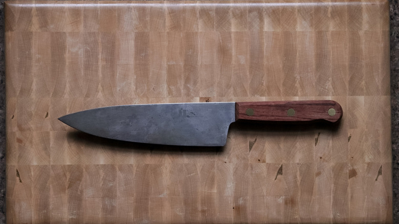 A carbon steel knife on a wooden cutting board