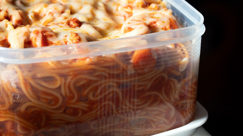 A plastic container with spaghetti in tomato sauce and cheese
