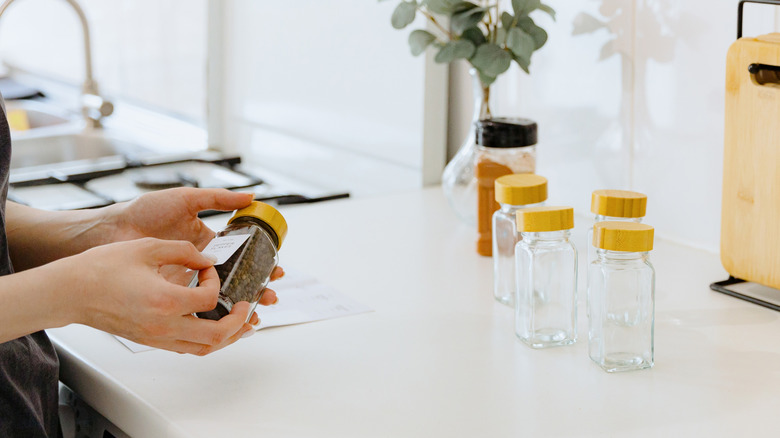 A woman peeling a sticker off a glass jar