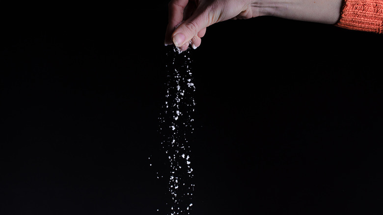 woman dropping pinch of salt