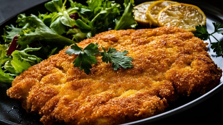 Breaded pork chop on black plate