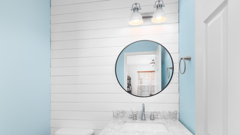 The interior of a small bathroom with white shiplap backsplash
