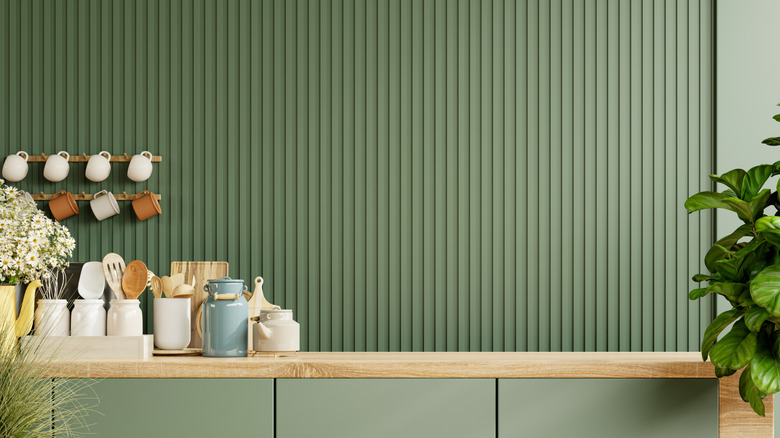 PVC paneling on a kitchen wall painted green, coffee mugs and containers displayed in front