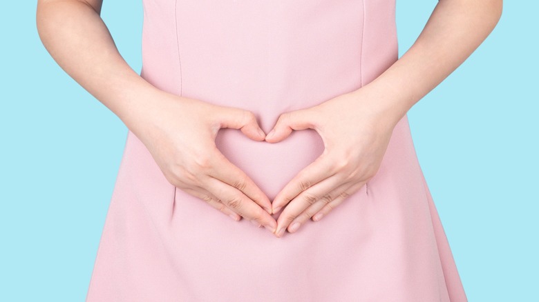 Woman hands in heart over tummy