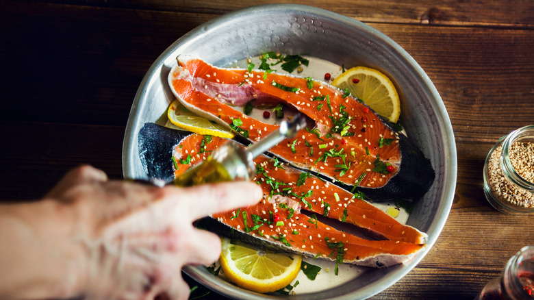 salmon being seasoned in pan