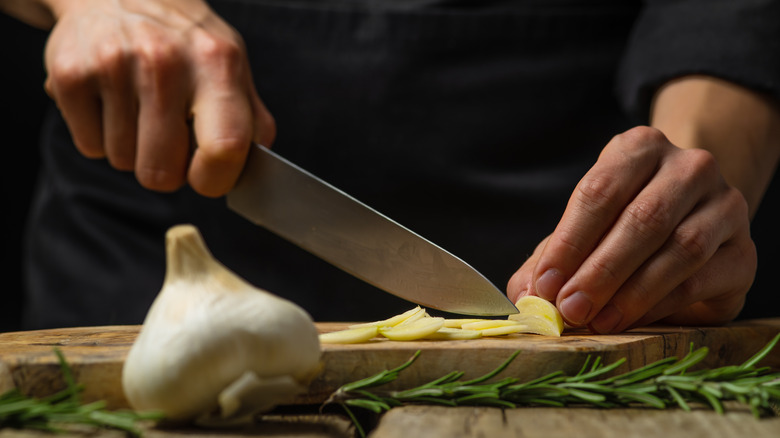 Person slicing garlic clove