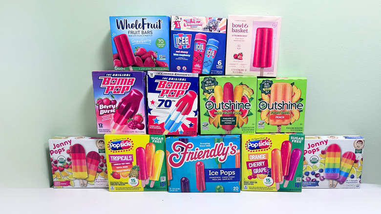 Several boxes of frozen fruit flavored popsicles together against a white and green background