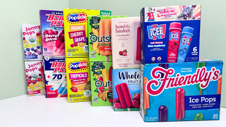Several boxes of frozen fruit flavored popsicles together against a white and green background