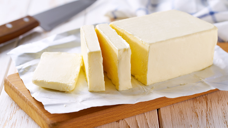 A sliced block of butter on a wooden board