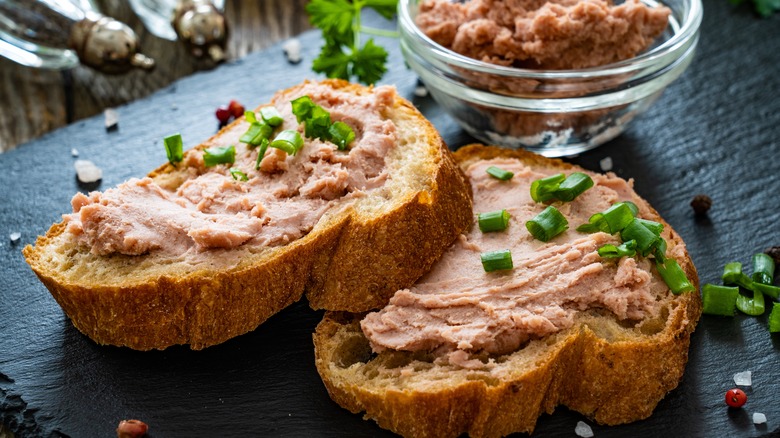 Liverwurst spread over bread and topped with sliced scallions