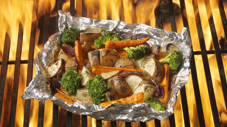Grilling potatoes, carrots, and broccoli in an aluminum foil packet on the grill