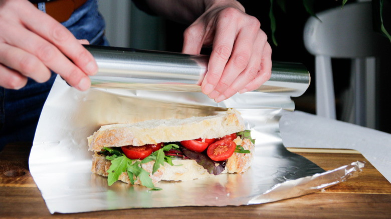 A sandwich being wrapped in aluminum foil