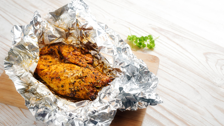 A piece of marinated meat wrapped in aluminum foil