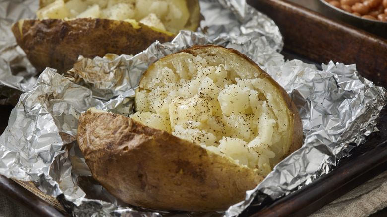 A seasoned baked potato in aluminum foil
