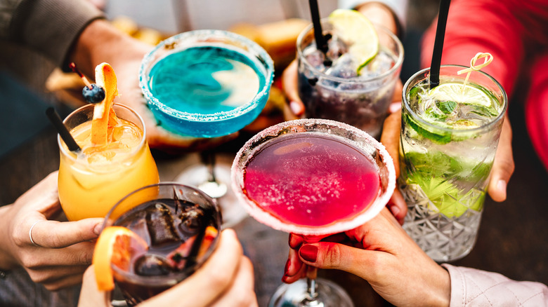 People toasting multicolored drinks