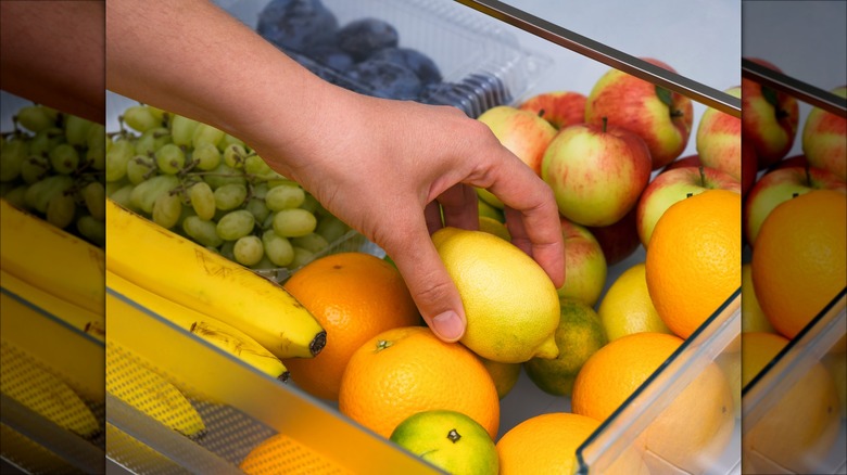 hand grabbing fruit from fridge drawer
