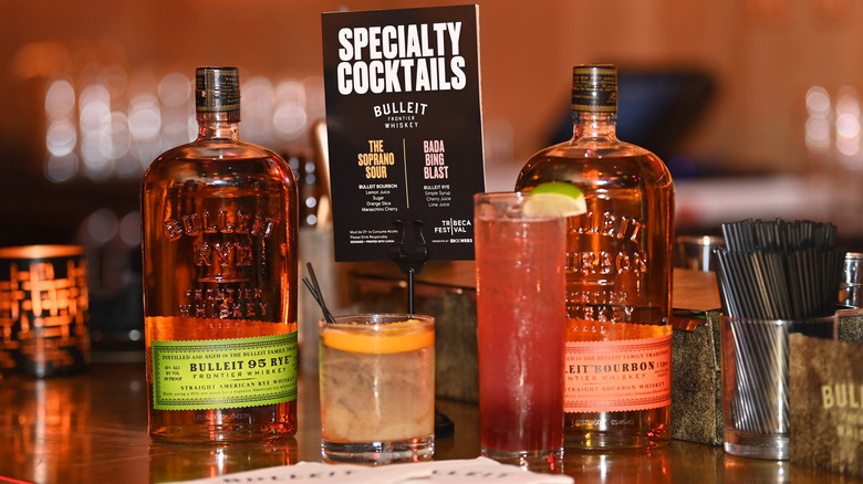 A bar table with bottles of Bulleit and specialty cocktails