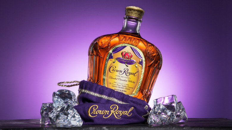 A bottle of Crown Royal Canadian Whisky with a purple bag and ice cubes