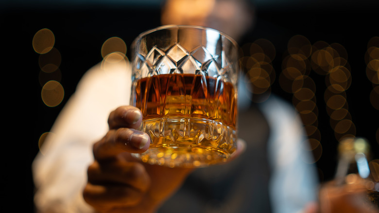A bartender handing a patron a glass of whiskey