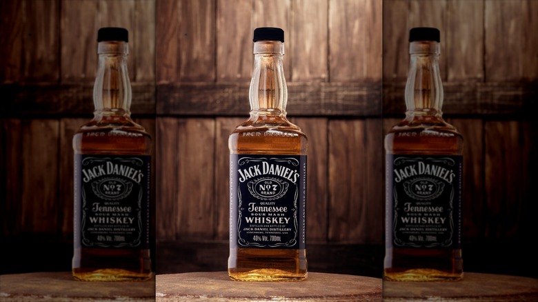 A bottle of Jack Daniel's Old No. 7 in front of a whiskey barrel